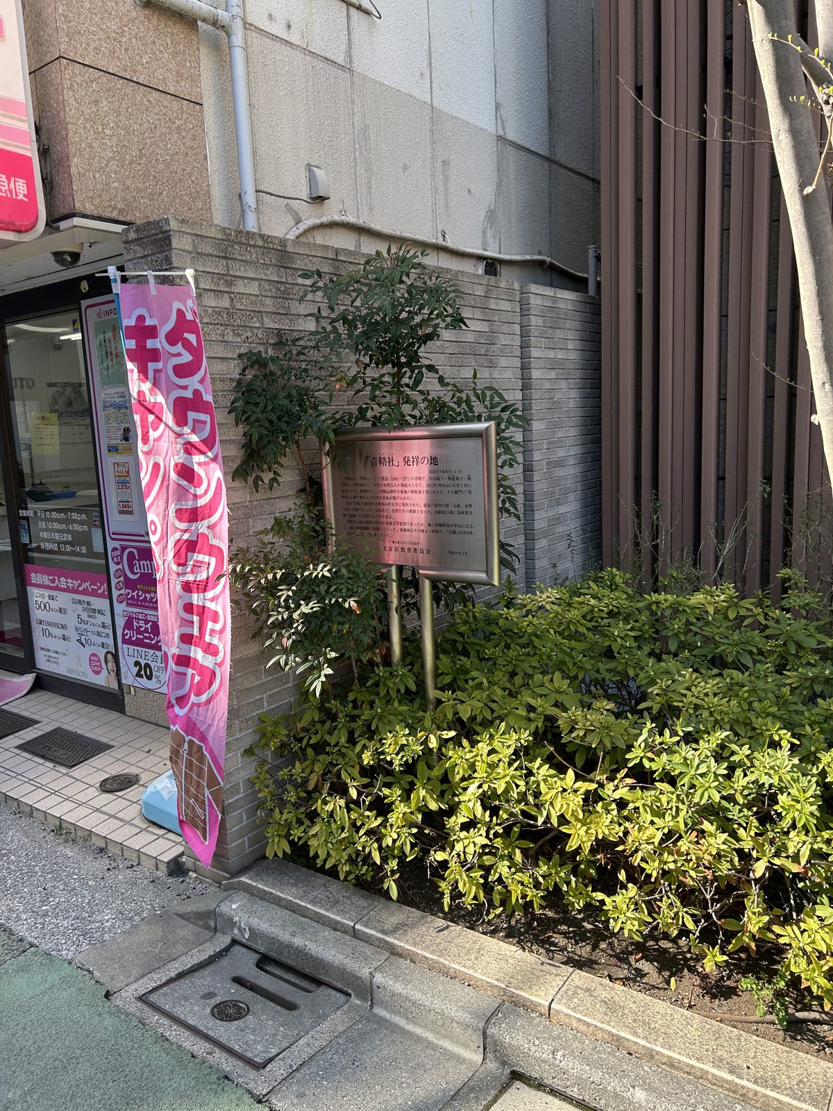 青鞜社发祥地如今的街景,铜牌立在一栋公寓外墙下,旁边是普通店铺